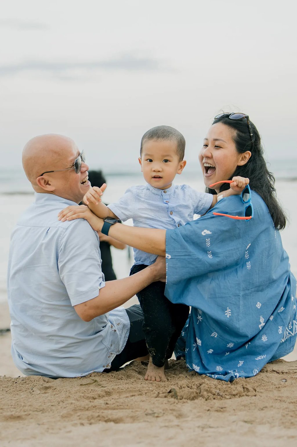 Parents laughing with their son during a candid family photography session at Nusa Dua Beach