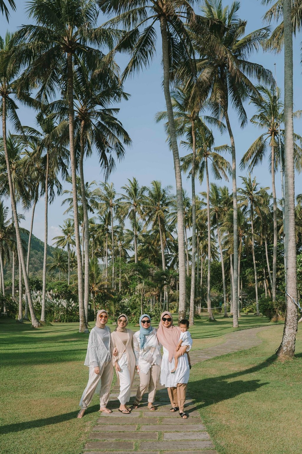 Group of women walking through palm garden during photoshoot at Candi Beach Resort Karangasem Bali