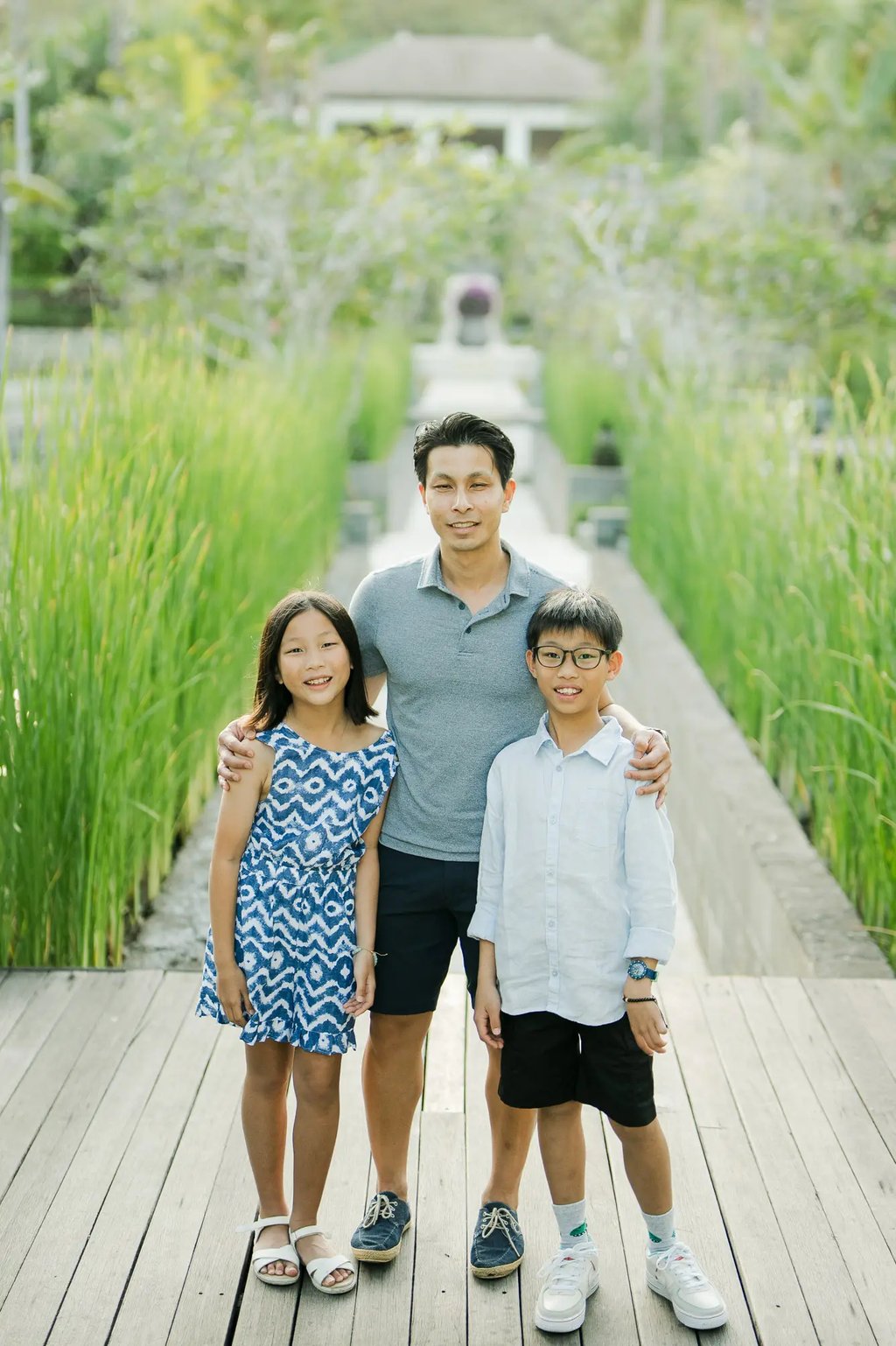 Family standing together on a tropical garden boardwalk during a luxury family photography session at The Ritz-Carlton Bali.