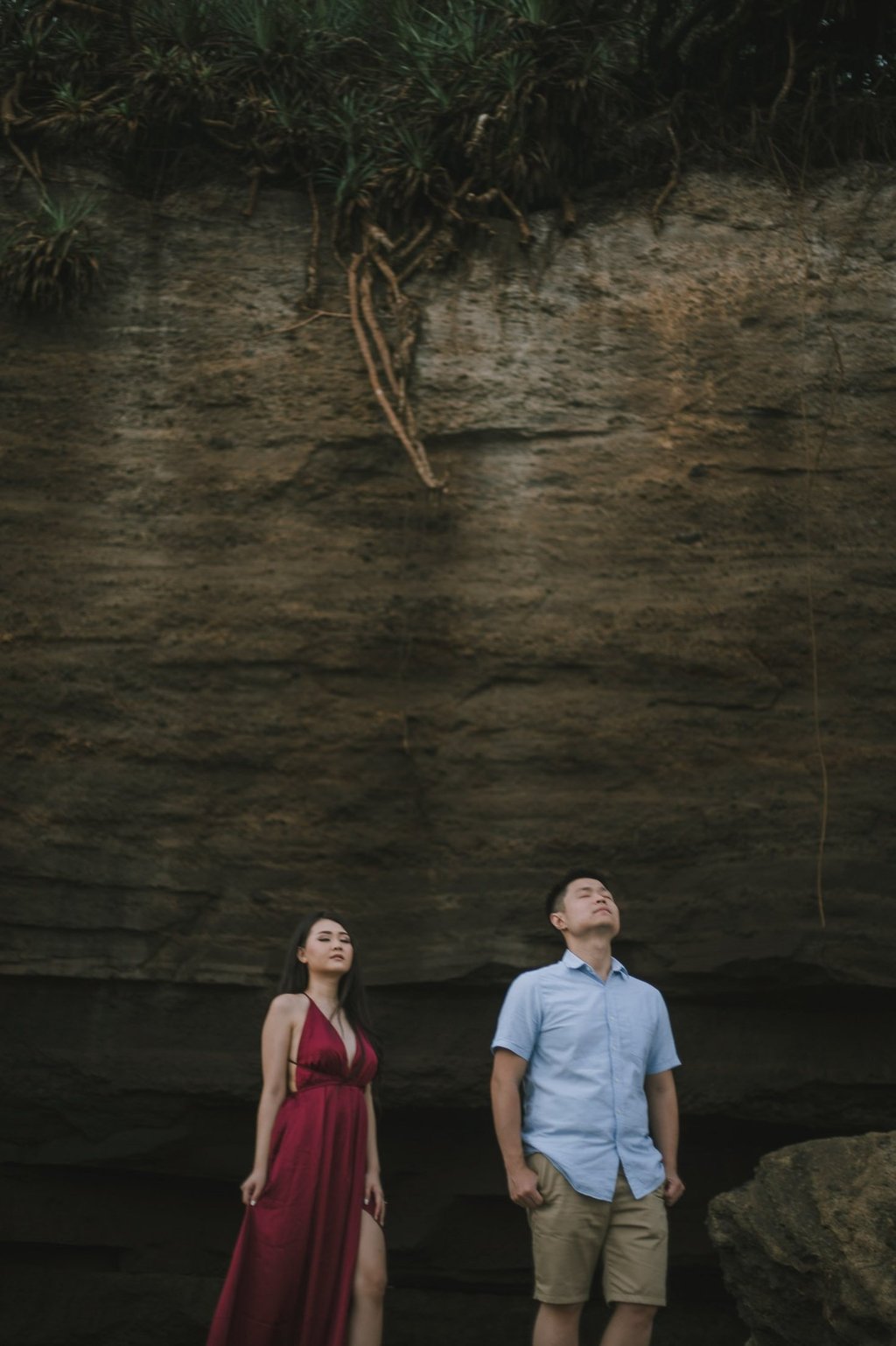 Romantic couple standing under cliff wall at Pantai Nyanyi Bali during sunset.