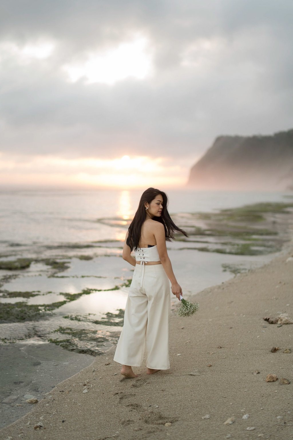 Bride walking along coastal shoreline during sunset at Melasti Beach Bali