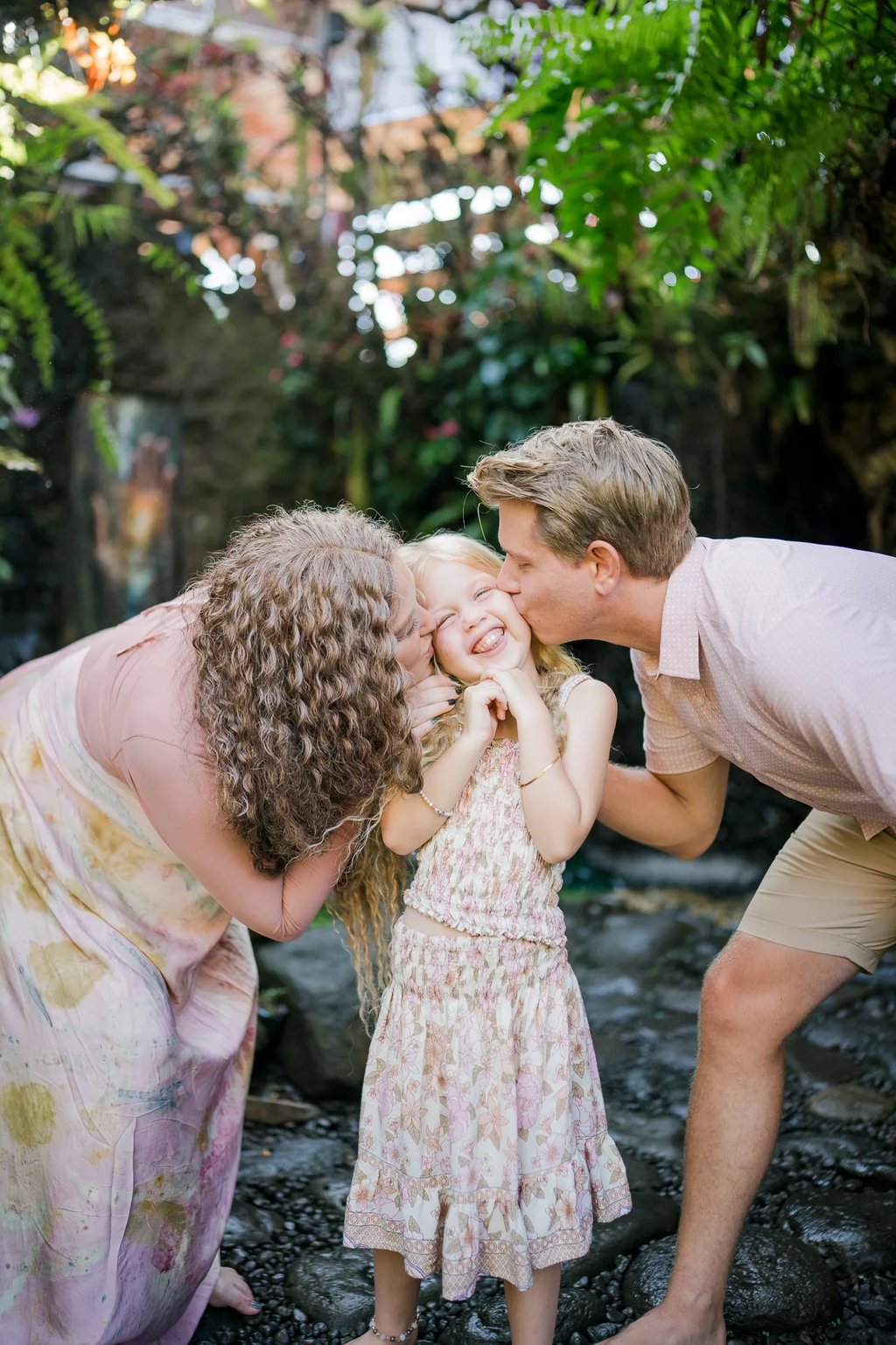 Parents kissing their daughter during a natural family photography session in Ubud Bali