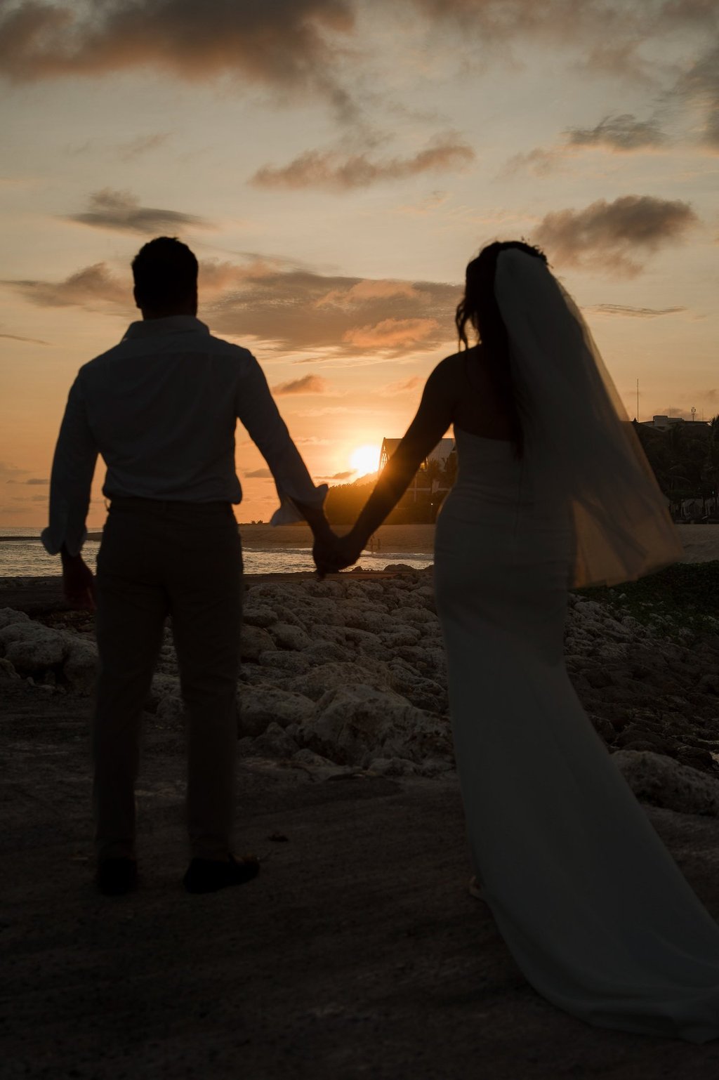 Silhouette of a couple holding hands during sunset prewedding photoshoot at Apurva Kempinski Bali beach