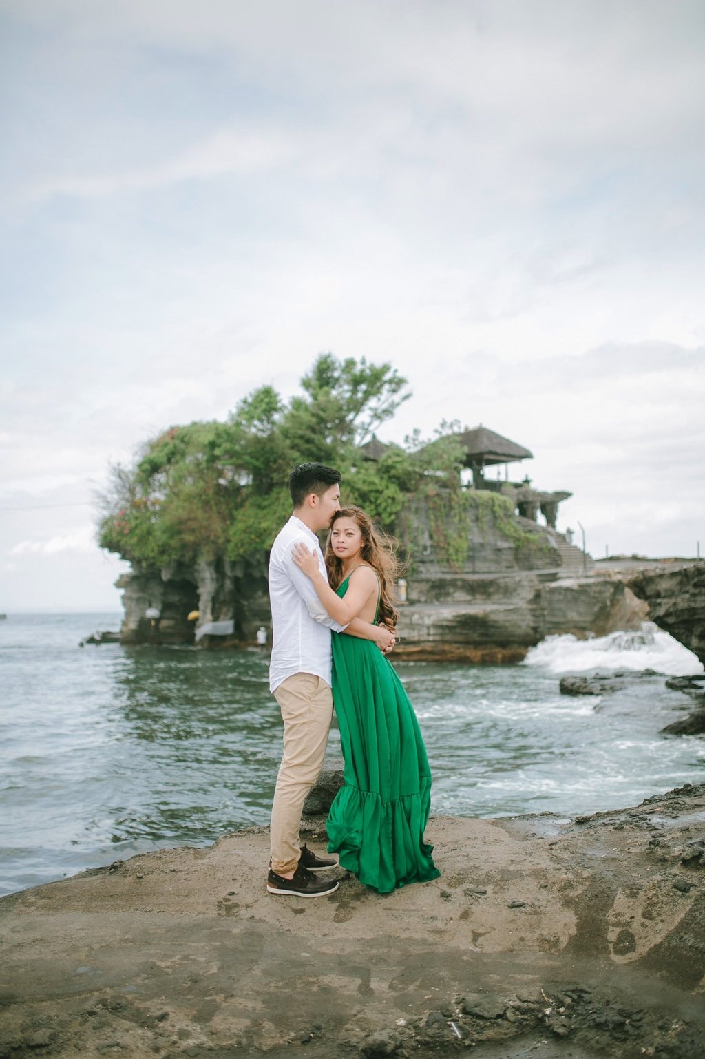 Romantic couple embracing near the ocean cliffs at Tanah Lot Bali.