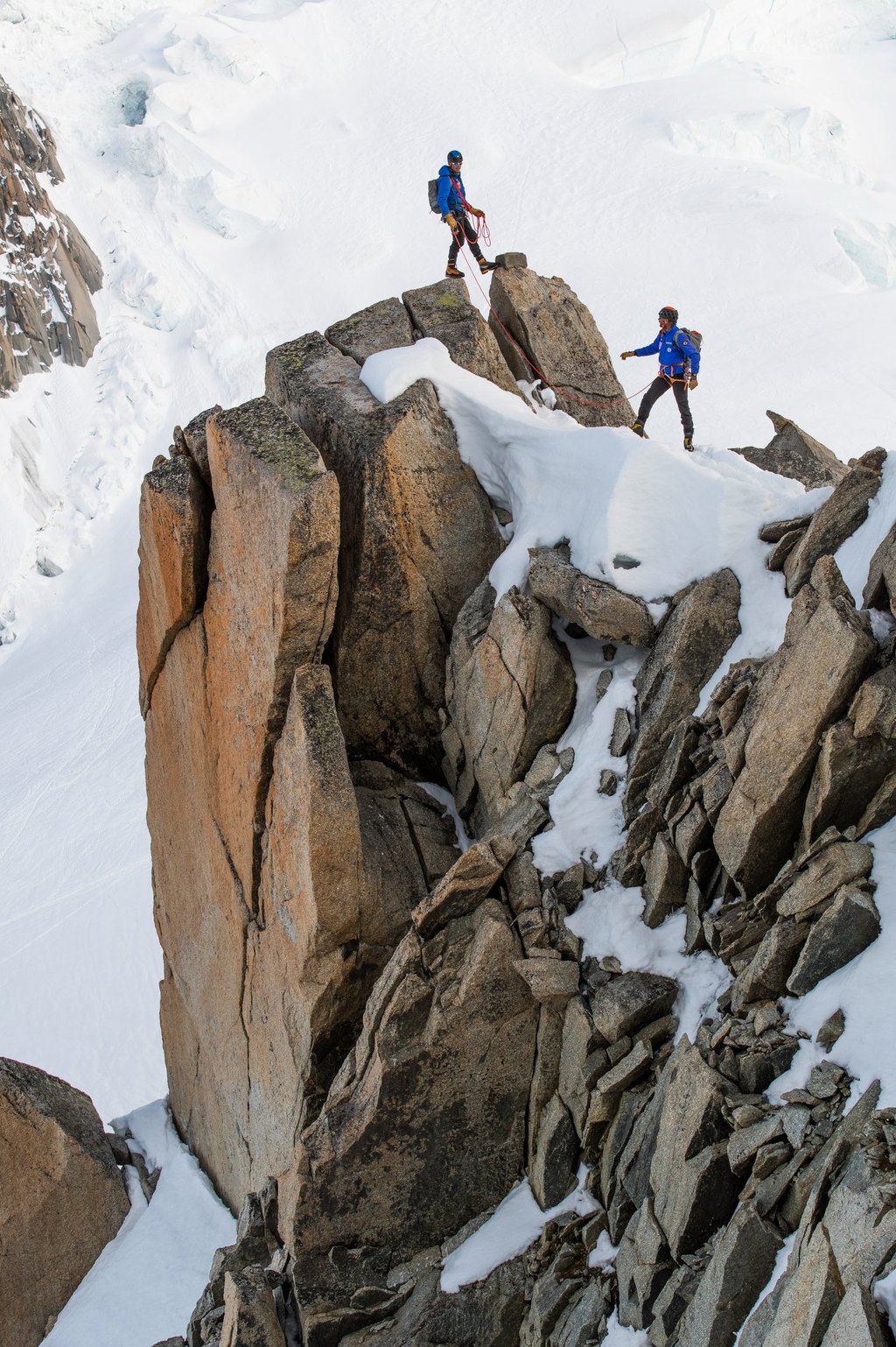 deux alpinistes sur une arrête rocheuse enneigée