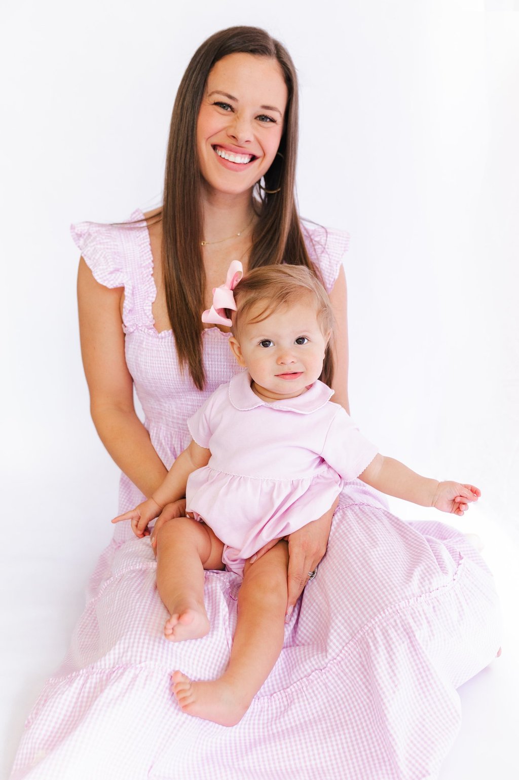 a mom in a pink dress sitting with her baby on her lap in a pink bubble