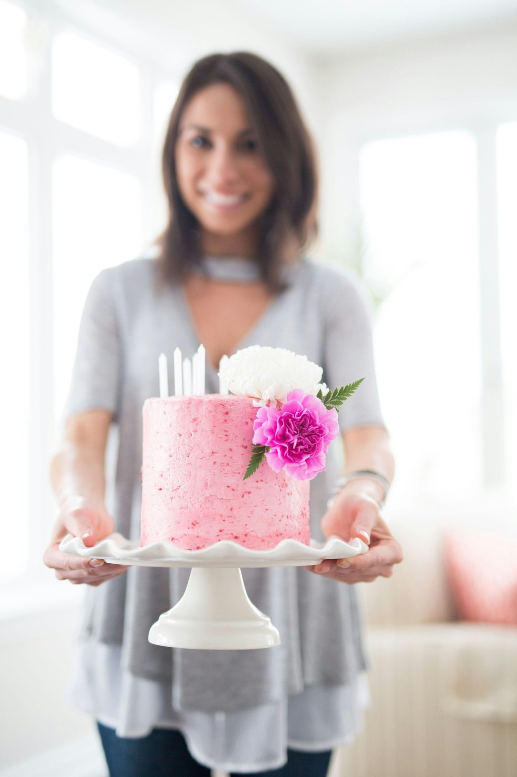 a woman holding a cake with candles and flowers.Tourism Consulting in England, Spain, Hungary