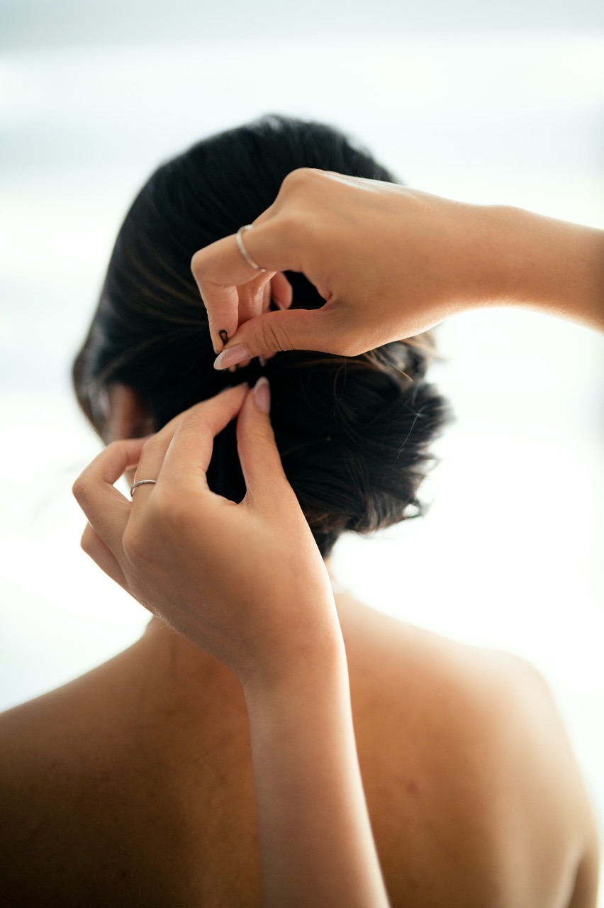 coiffeuse qui ajoute une bobbipin dans les cheveux de la mariée