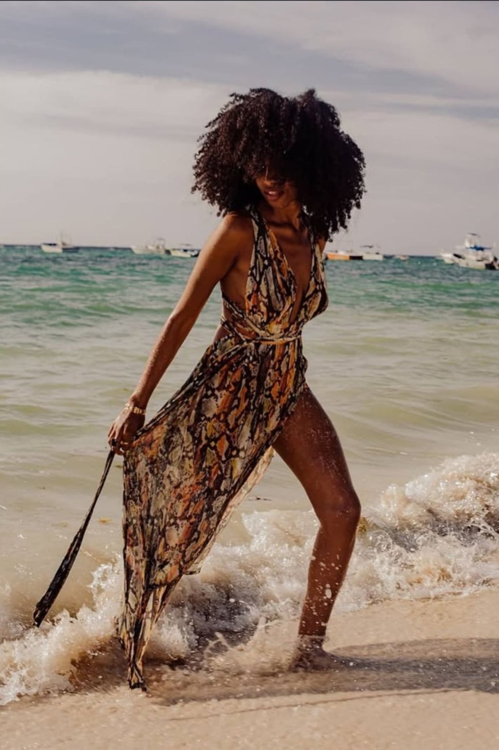 mujer morena con afro y con vestido boho en tulum en la playa