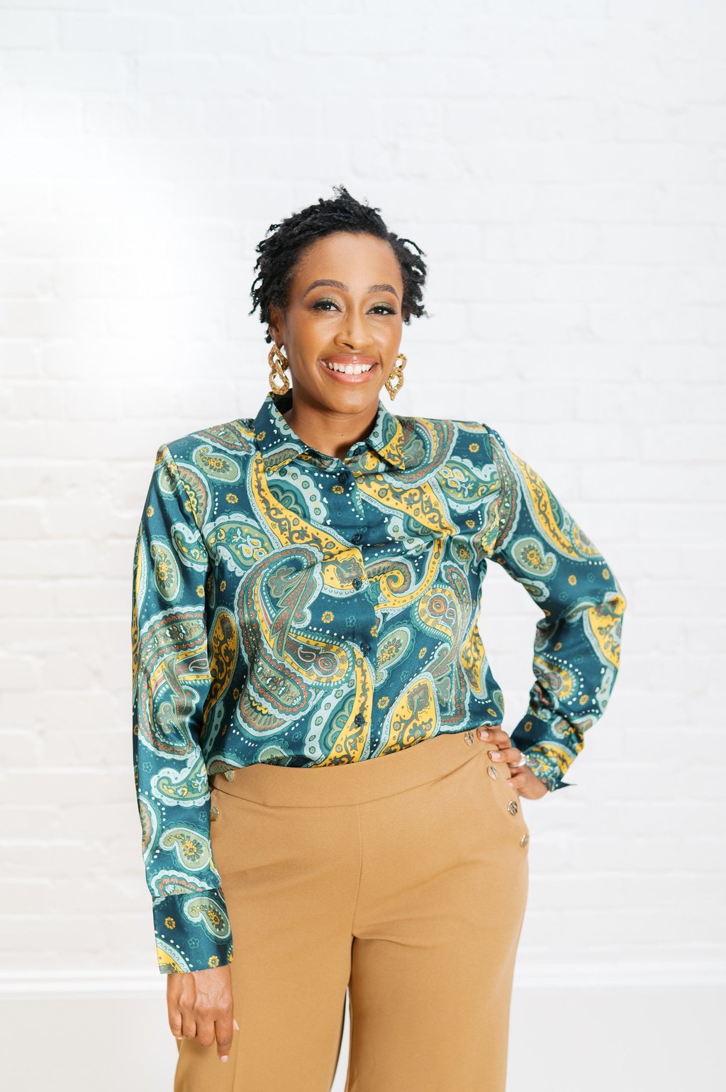 a woman in a blue paisley shirt and tan pants
