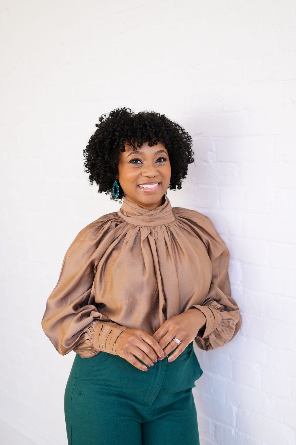 a woman in a brown blouse and green pants