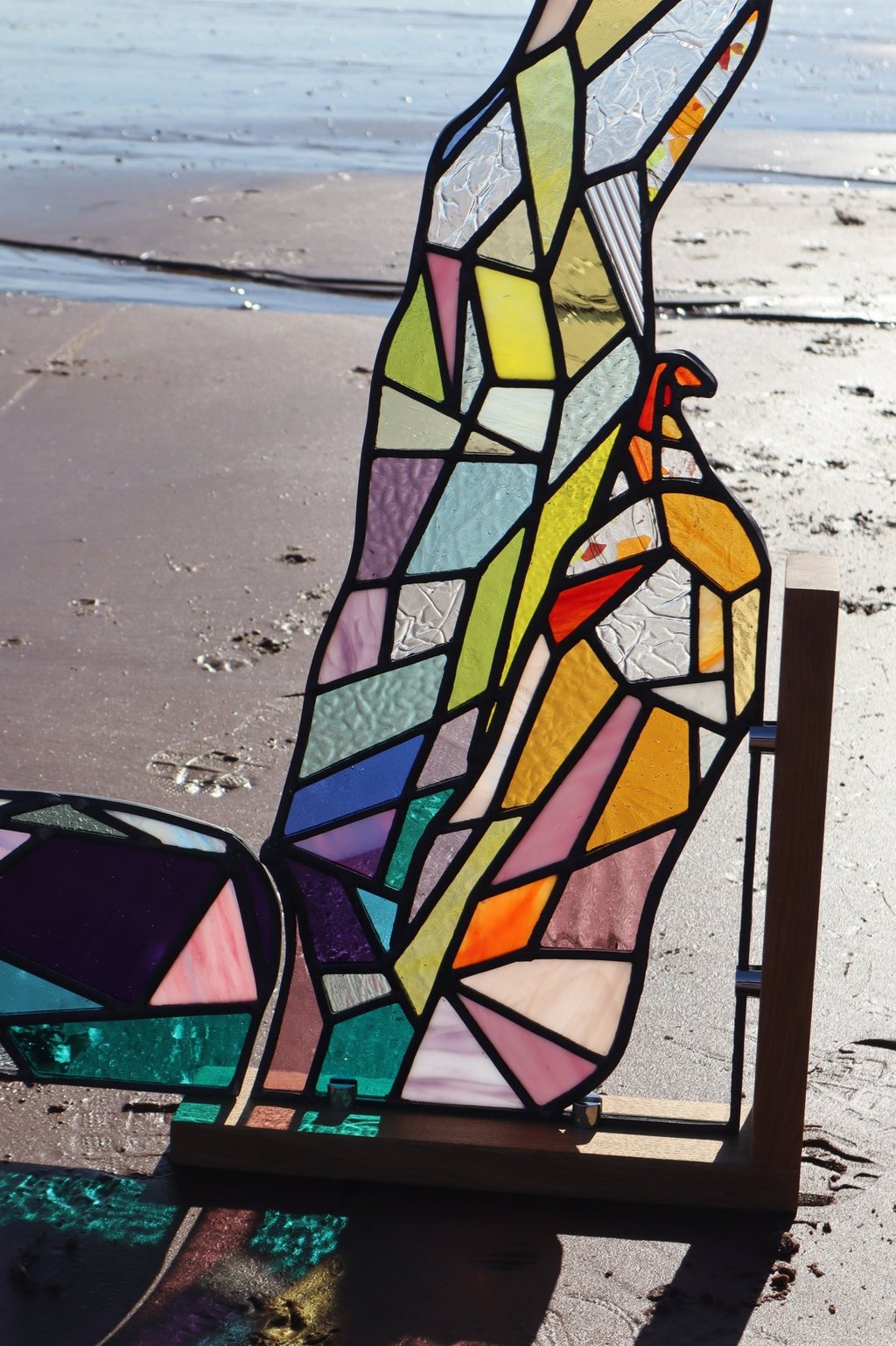 Full Sized Stained Glass Woman. Photograph is taken on a beach at low tide. Art work by Laura Kriefman