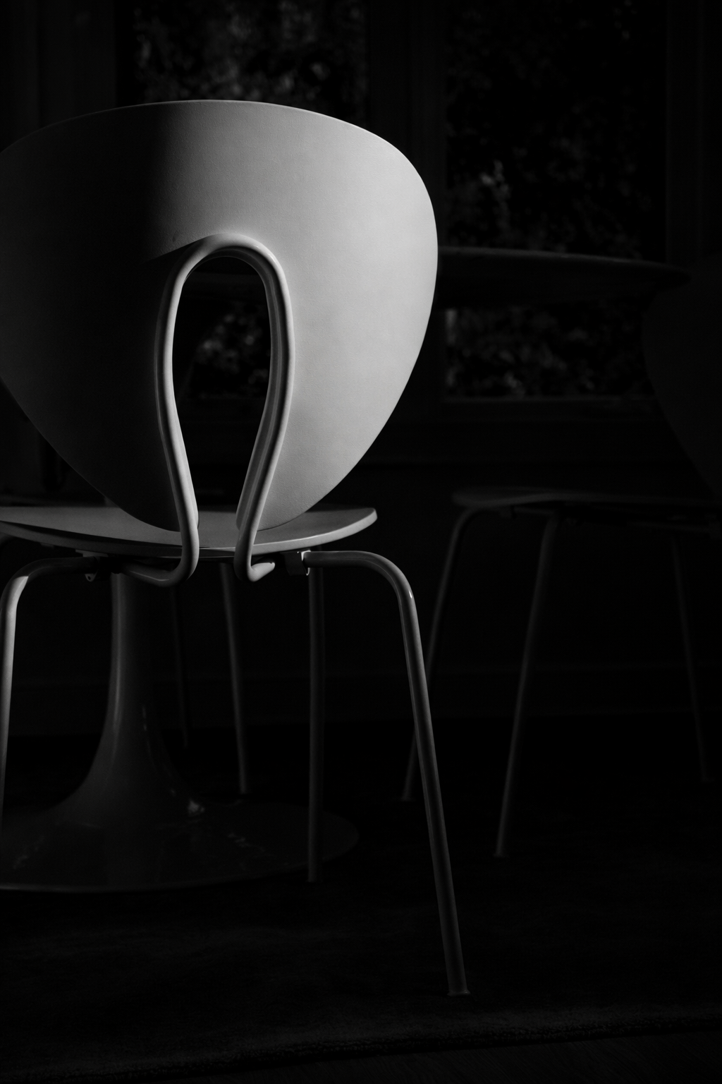 white sculptural chair with curved back, dramatic shadow and minimal interior setting