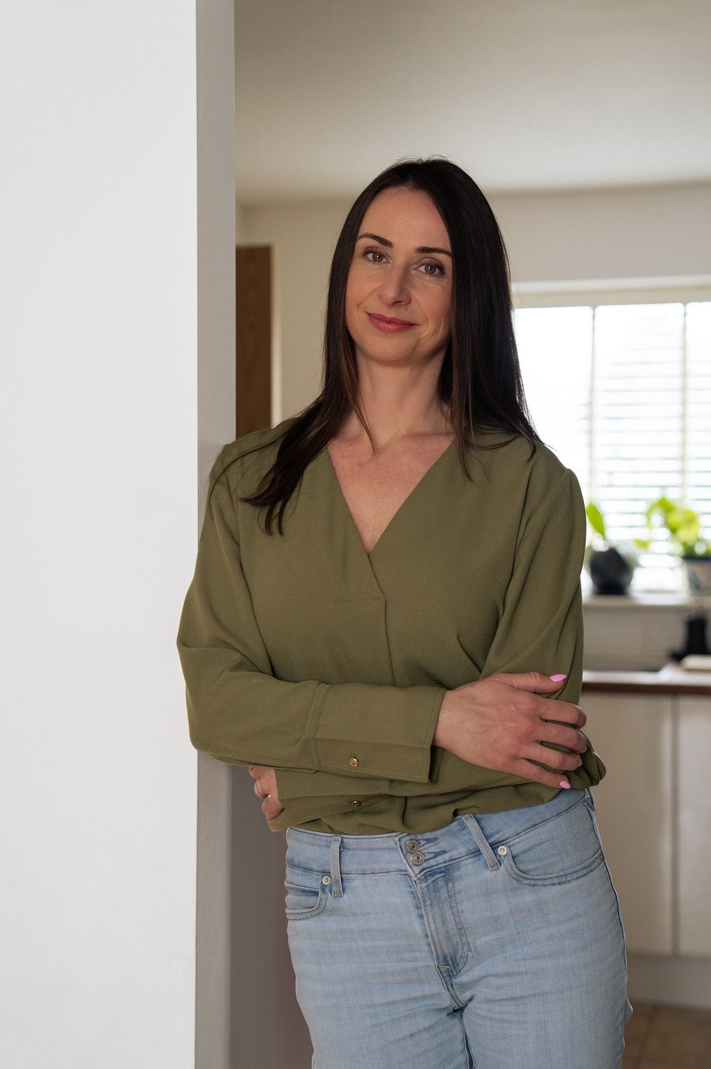 woman leaning on the wall with crossed arms smiling