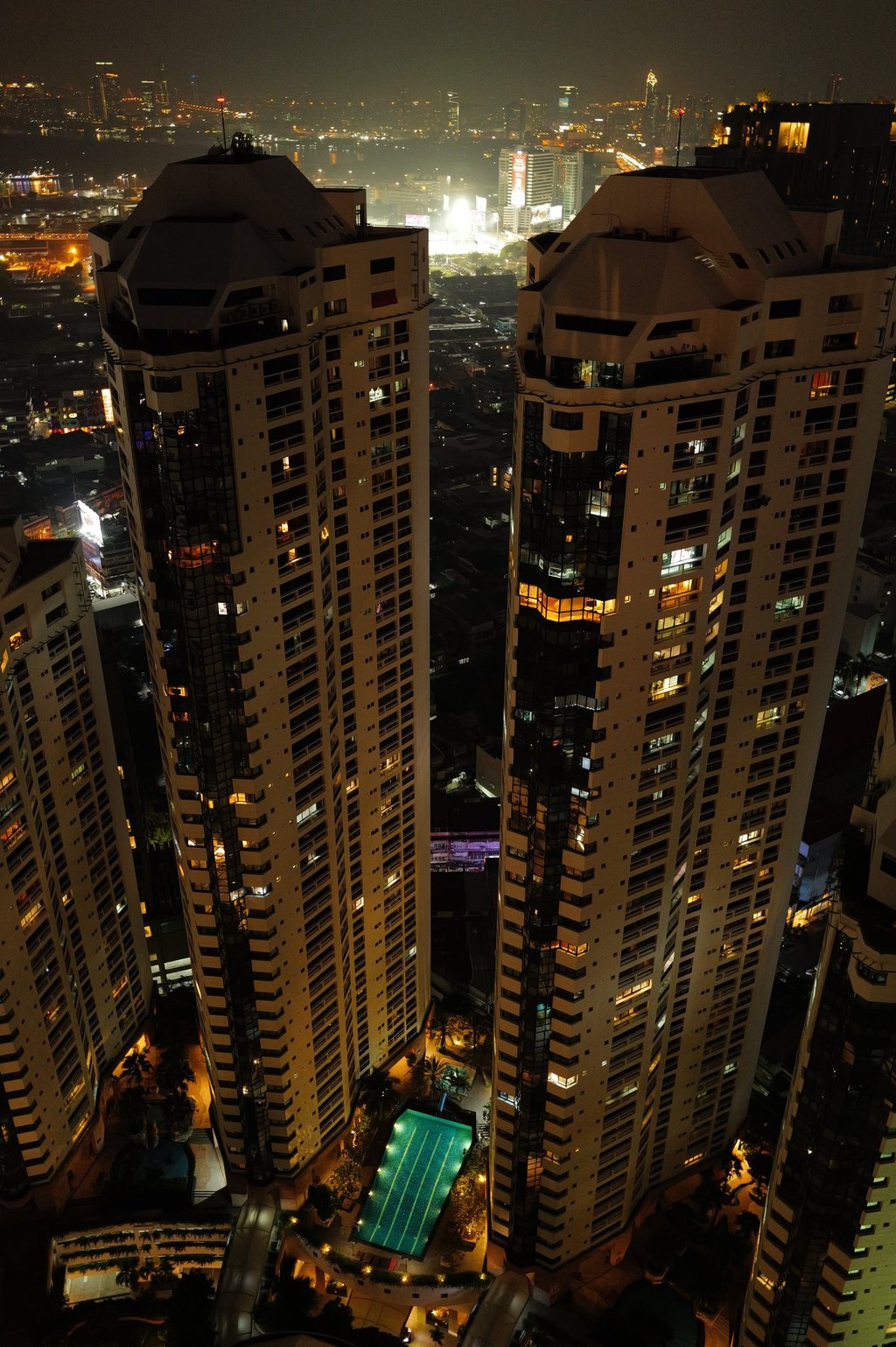 Night aerial view of twin towers in bangkok with pool below, By ACAT Photos