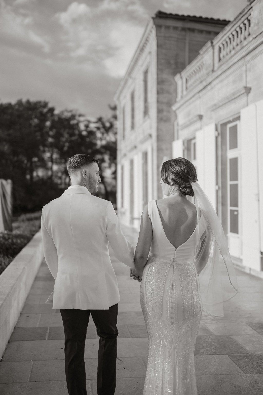 a bride and groom walking down a sidewalk wedding in Bordeaux Château Gassies