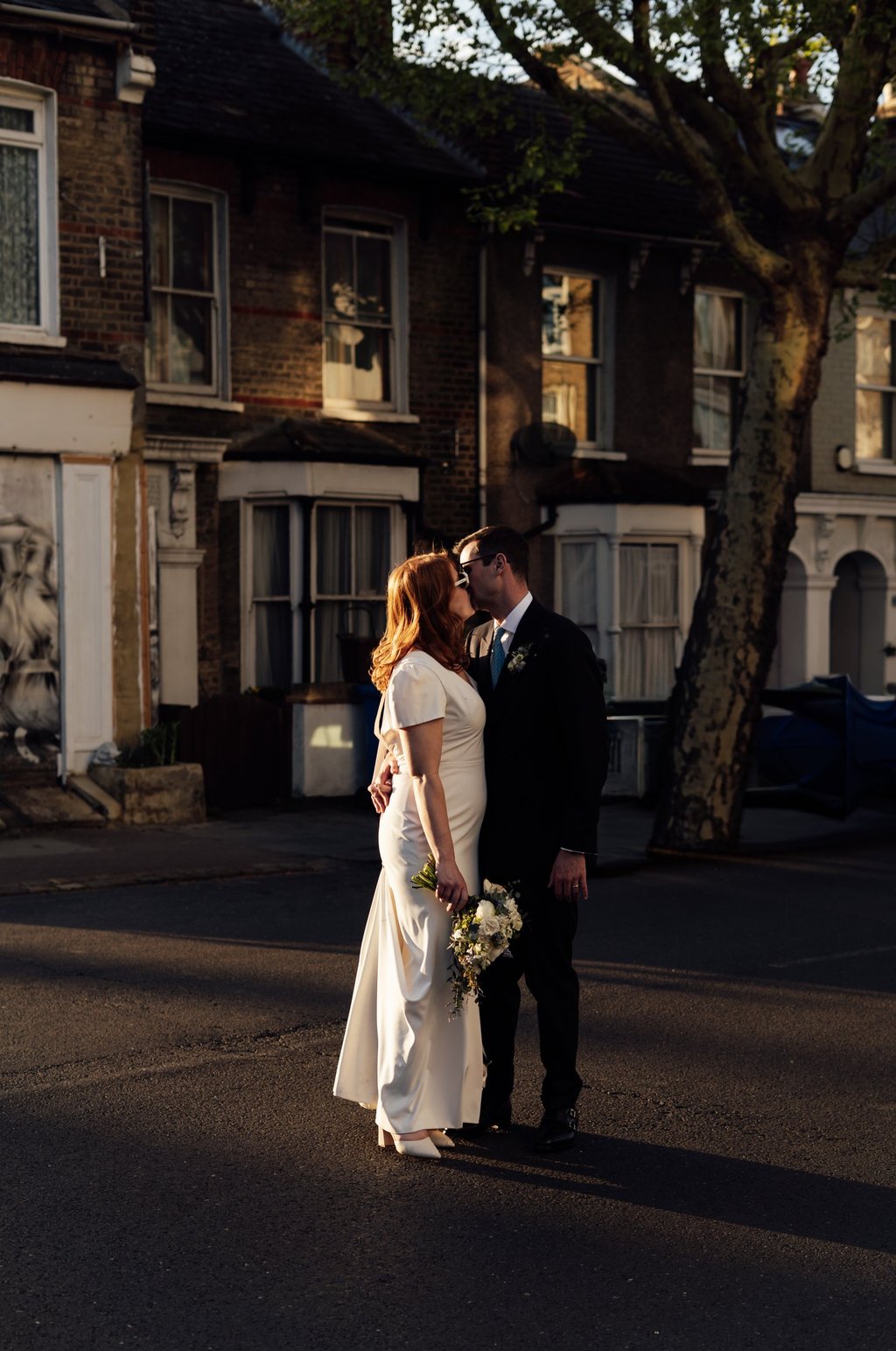 bride and groom standing on the street and kissing during the golden hour