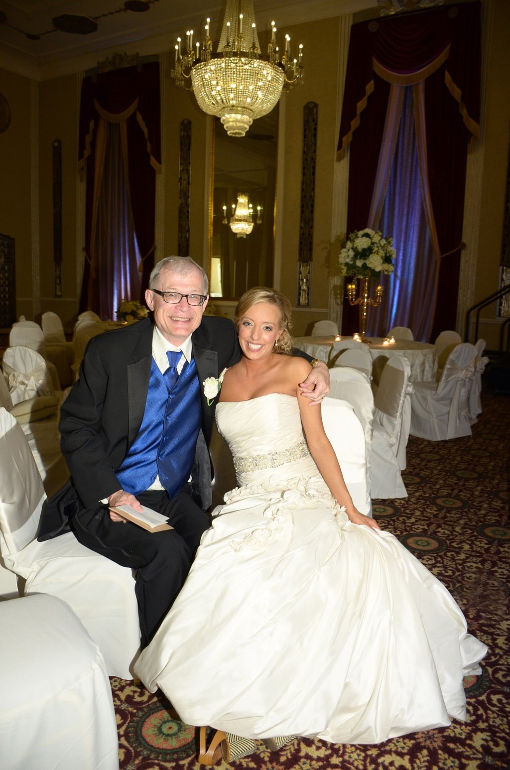 a bride and father-in-law sitting next to each other on in a ball room