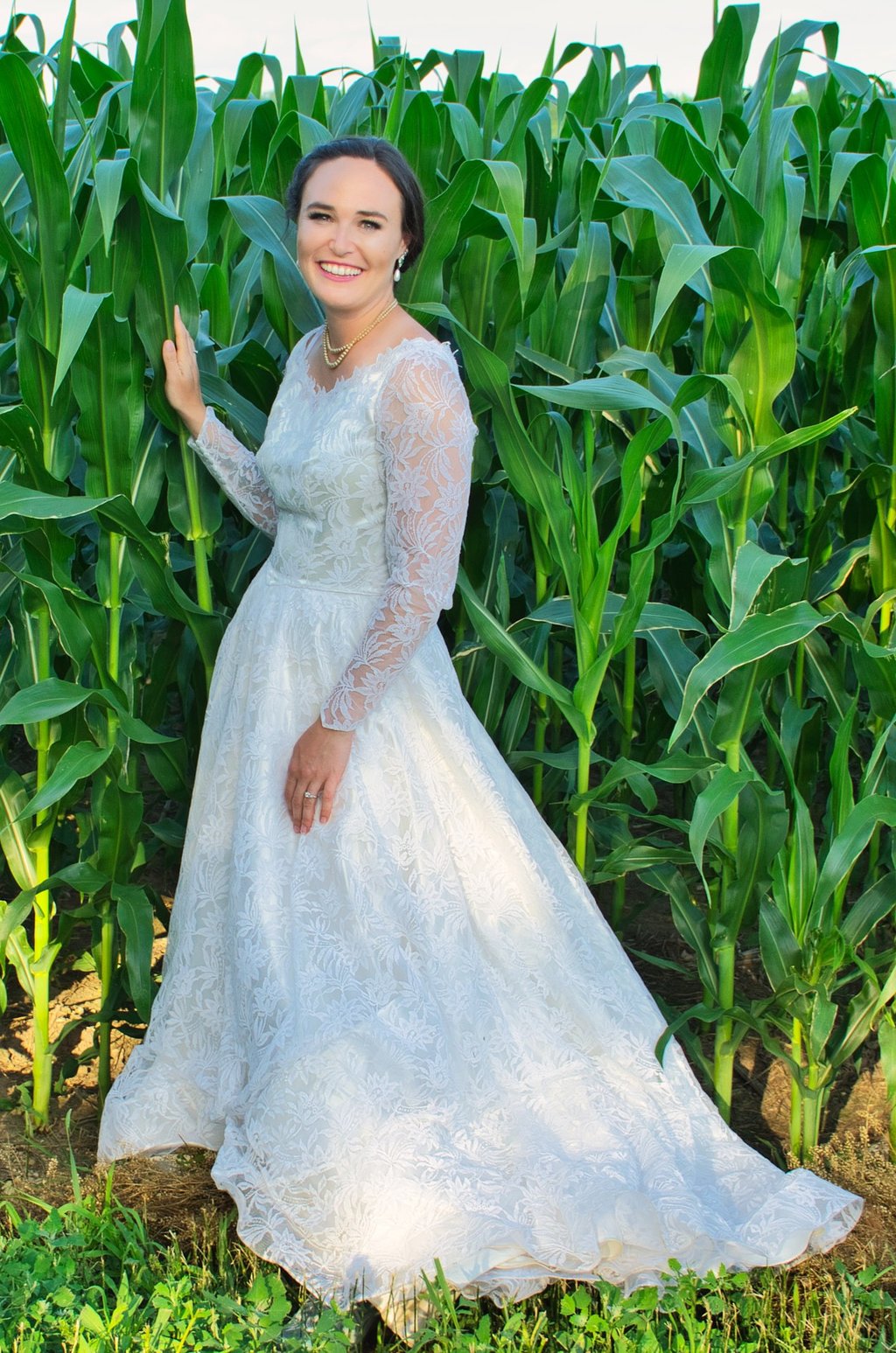 a woman in a white dress standing in front of a corn field