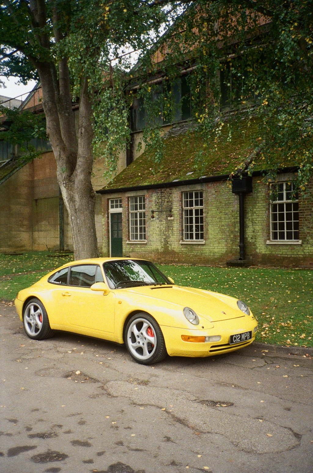 a yellow Porsche parked in front of a brick building