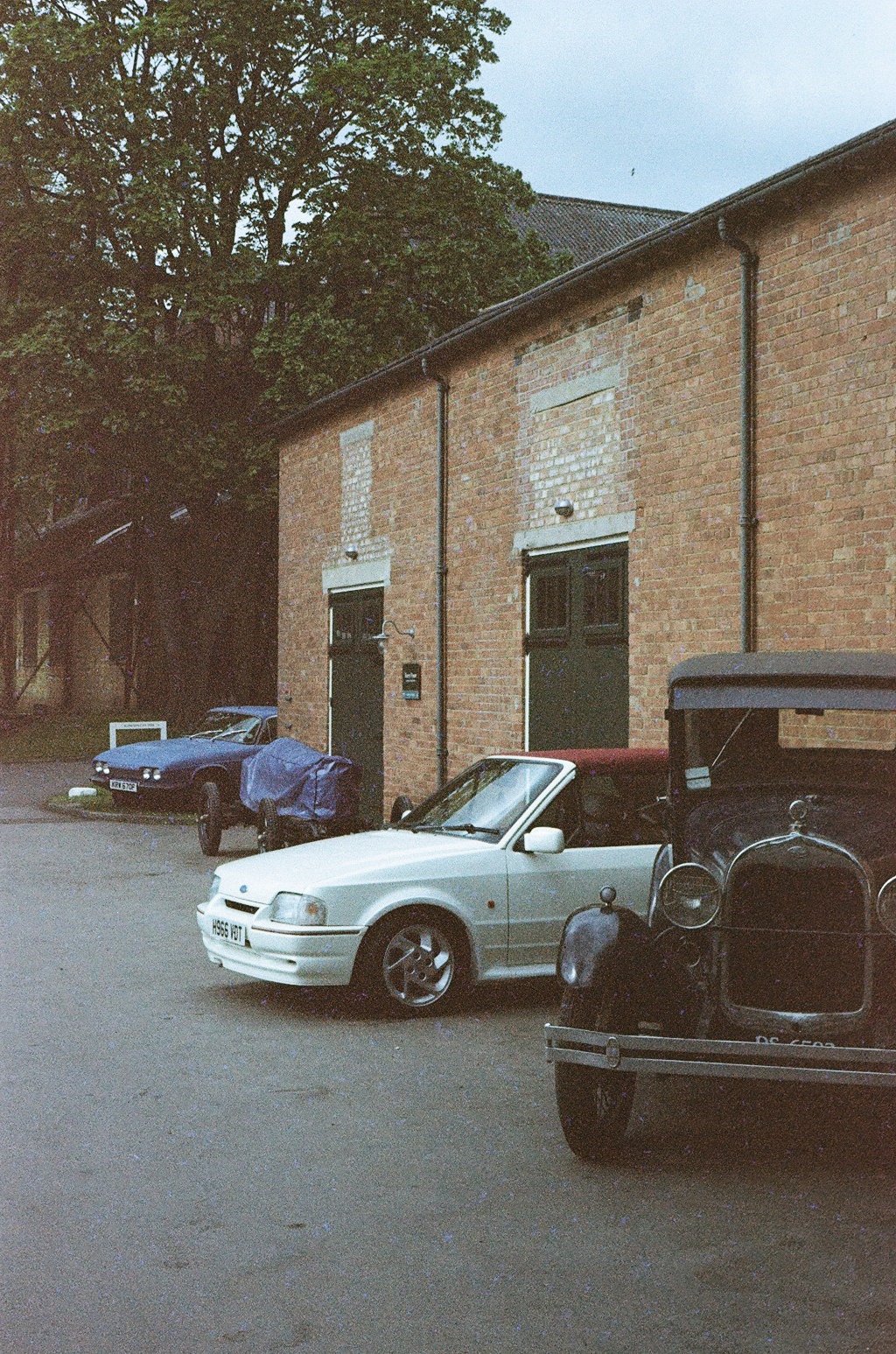 a selection of classic cars parked in front of a brick building