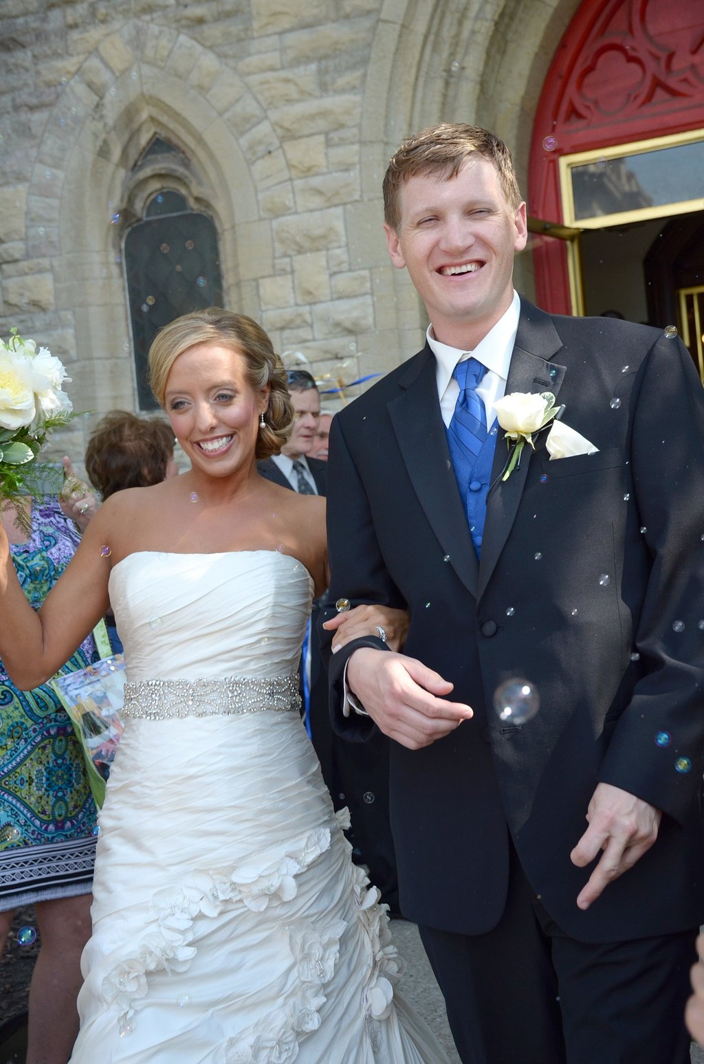 a bride and groom are walking our from the church and bubbles around them