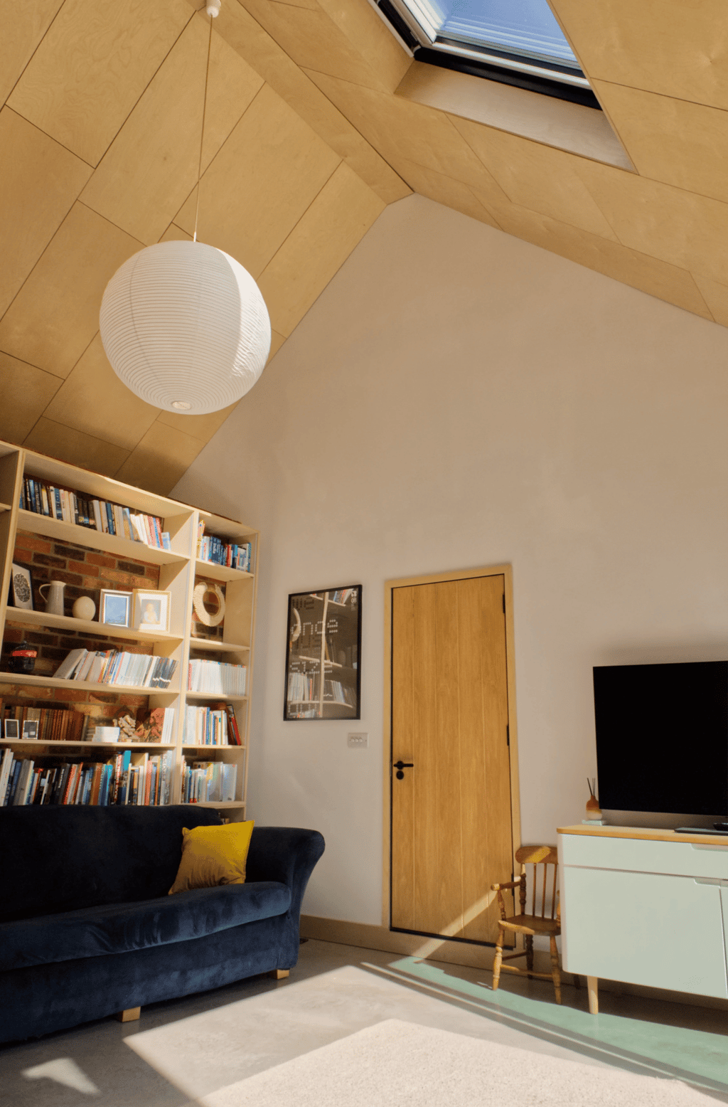 Modern interior living space. Interesting vaulted plywood ceiling and matching joinery.