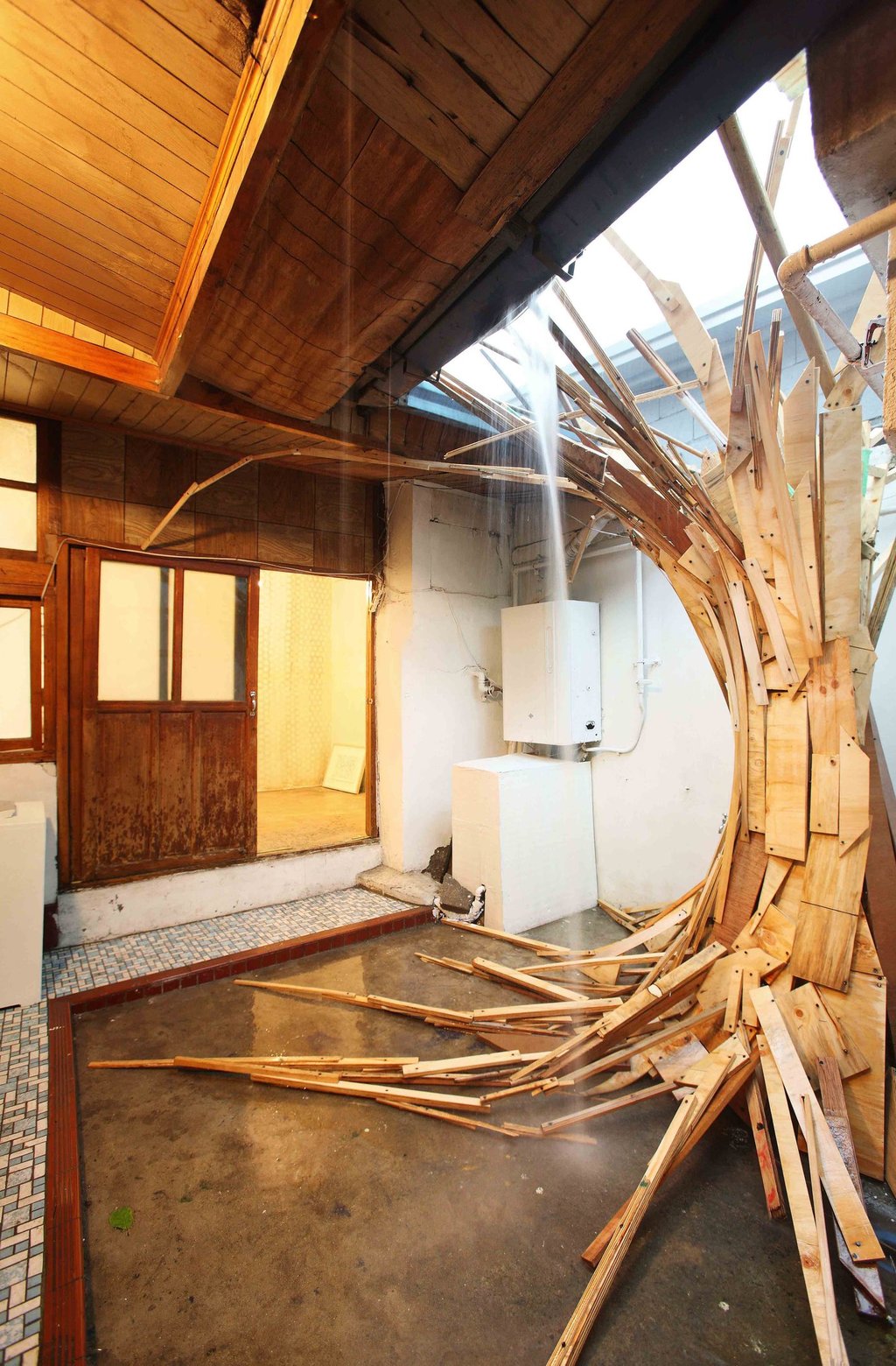 Indoor wooden plank art installation spiraling into a skylight with natural light.
