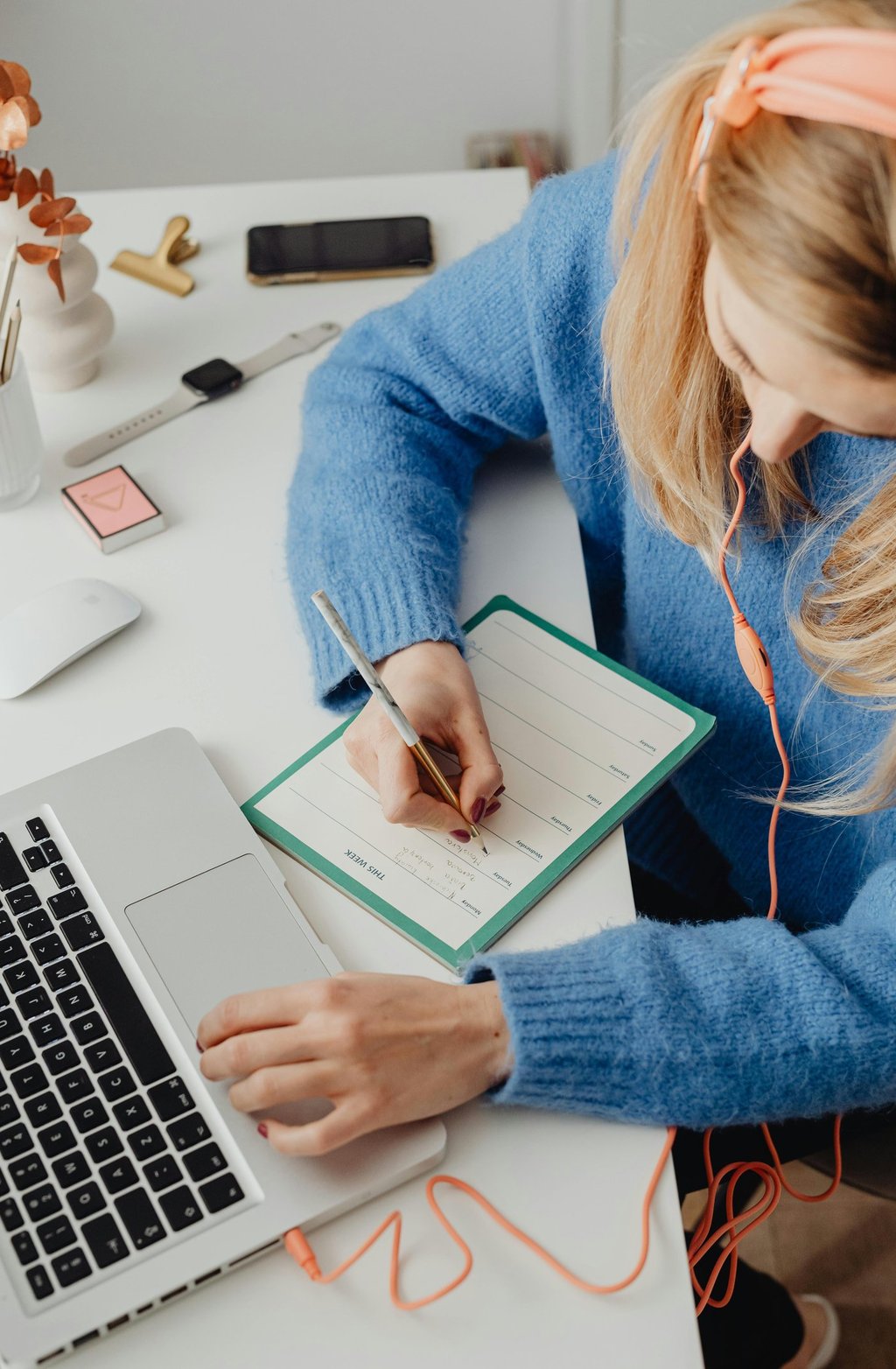 young woman working on her laptop with a notebook and coffee, planning her first online business from home