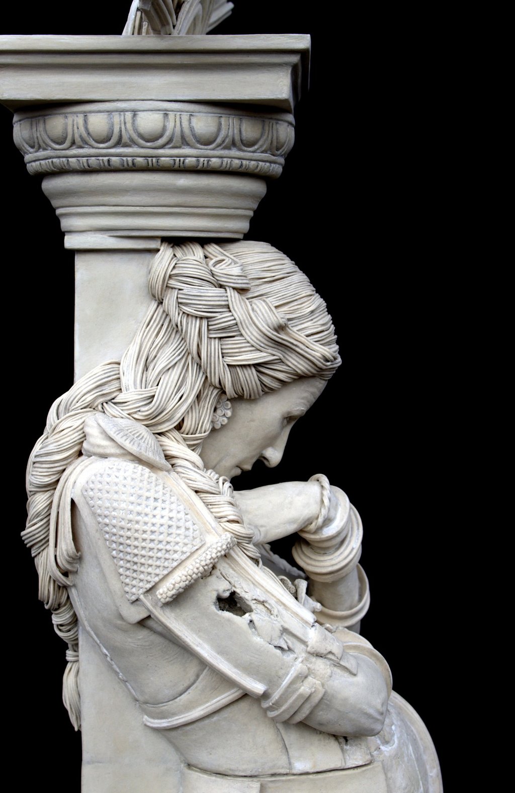 Closeup, right side of ceramic columnar woman sculpture, head weighted by capital, exploring social expectations.