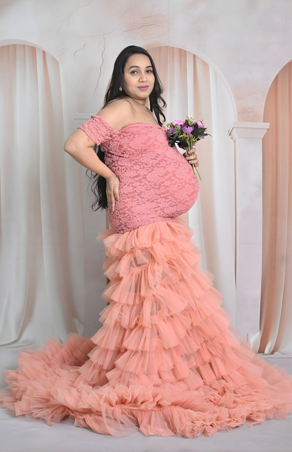 pregnant woman highlighting her baby bump against a studio backdrop.