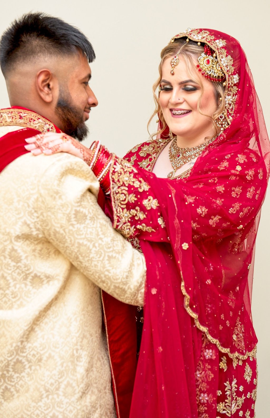 candid photo of bride and asian groom, bride's hand on groom shoulder, both laughing and having a good time