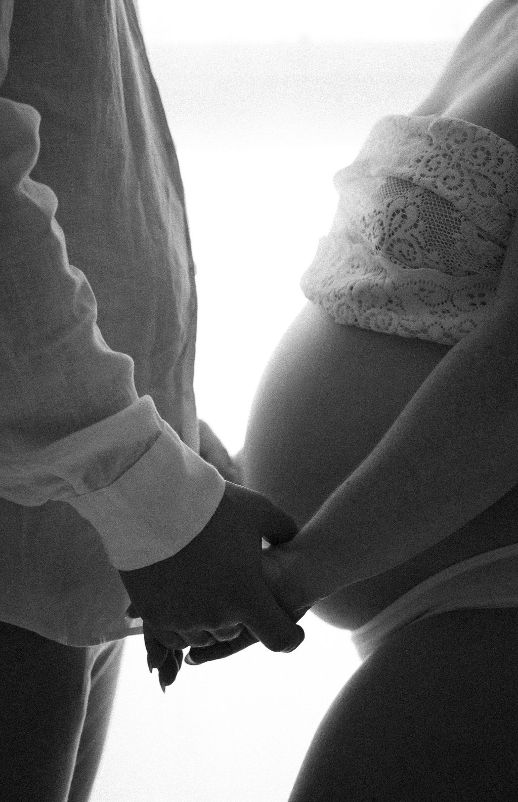 maternity photograph from the side of couple holding hands in a Littlehampton studio