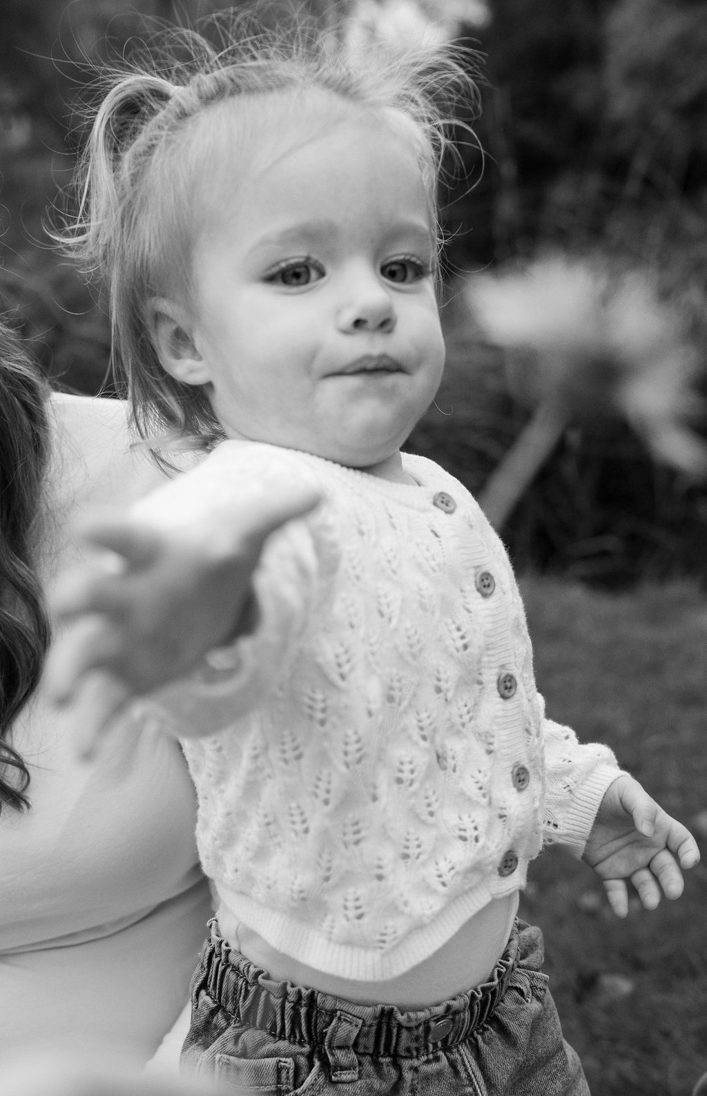 Black and white portrait of a girl reaching out for a flower