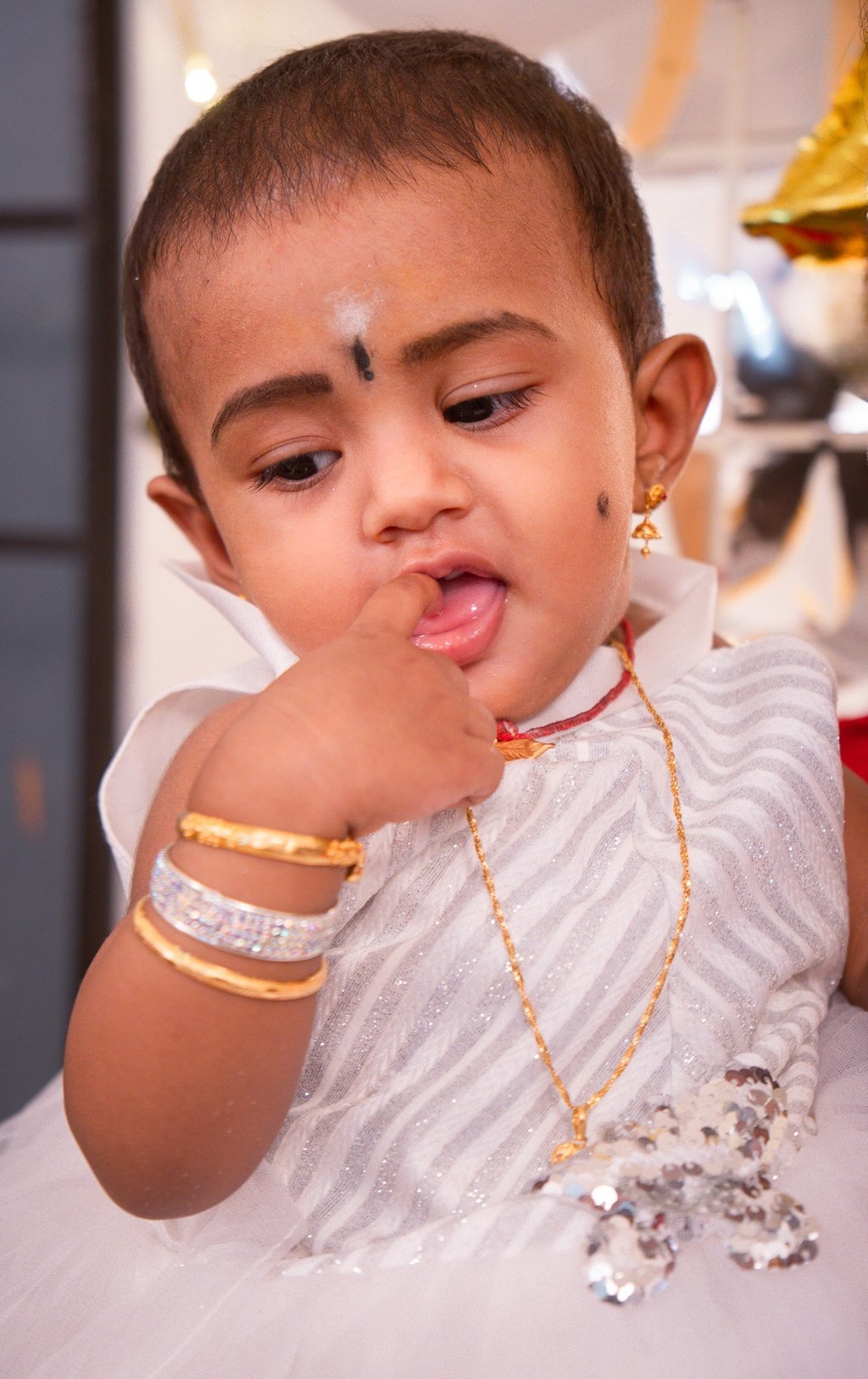a young child with a white dress and gold jewelry