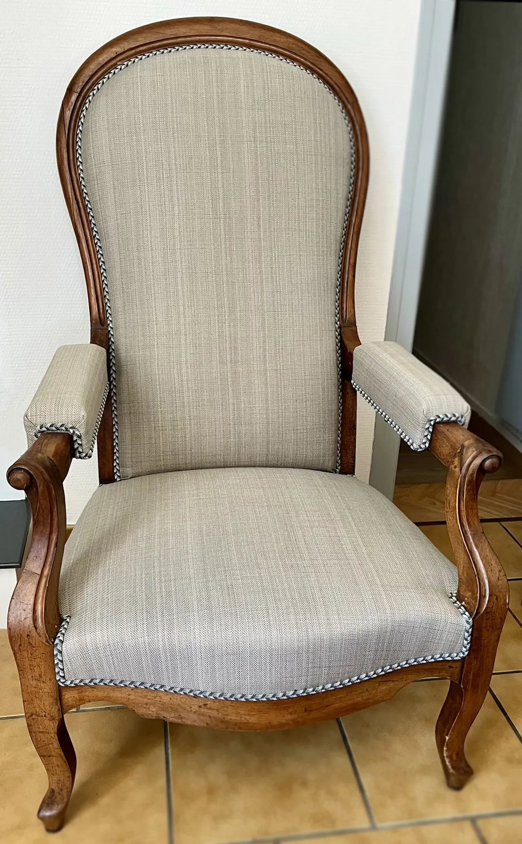 Chaise Voltaire avec assise en tissu gris et cadre en bois, dotée d'un dossier à bascule