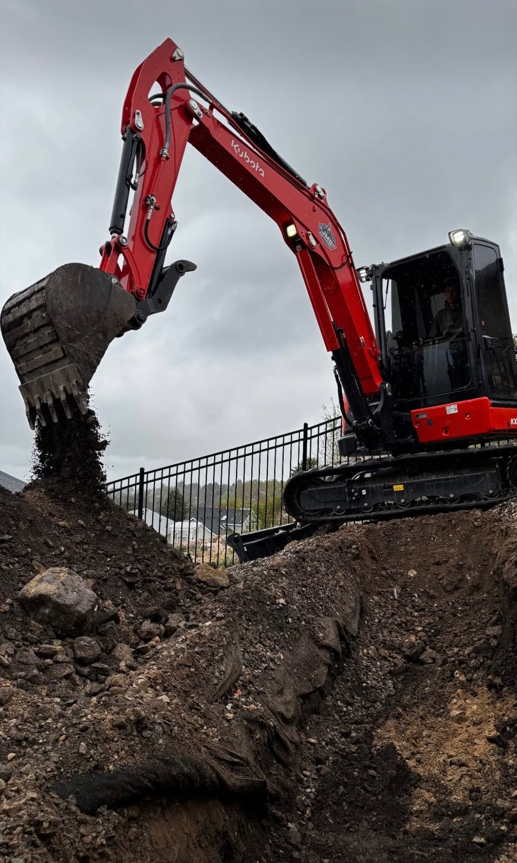 Kubota excavator digging dirt in residential backyard