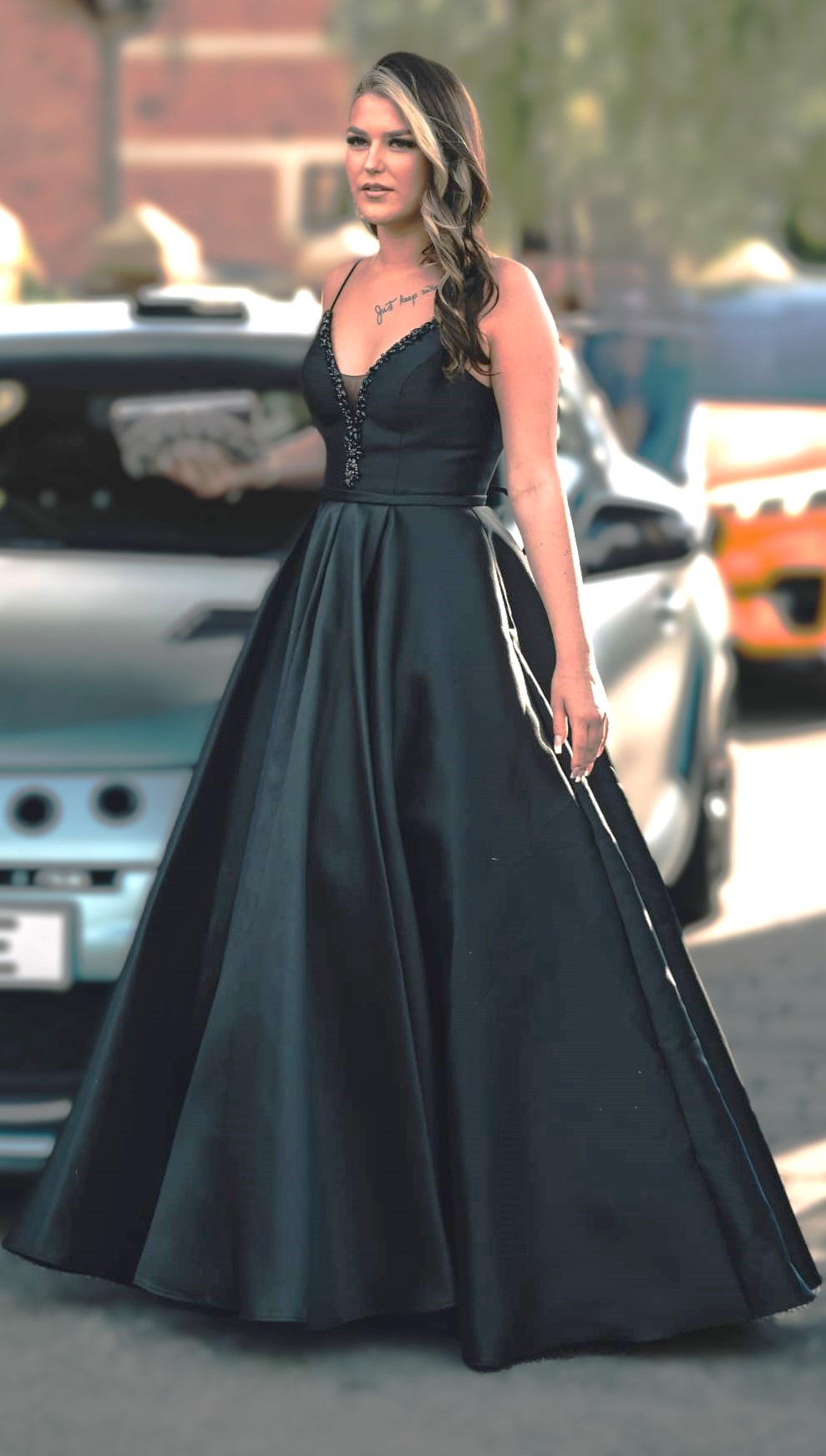 a woman in a black dress standing in front of a car