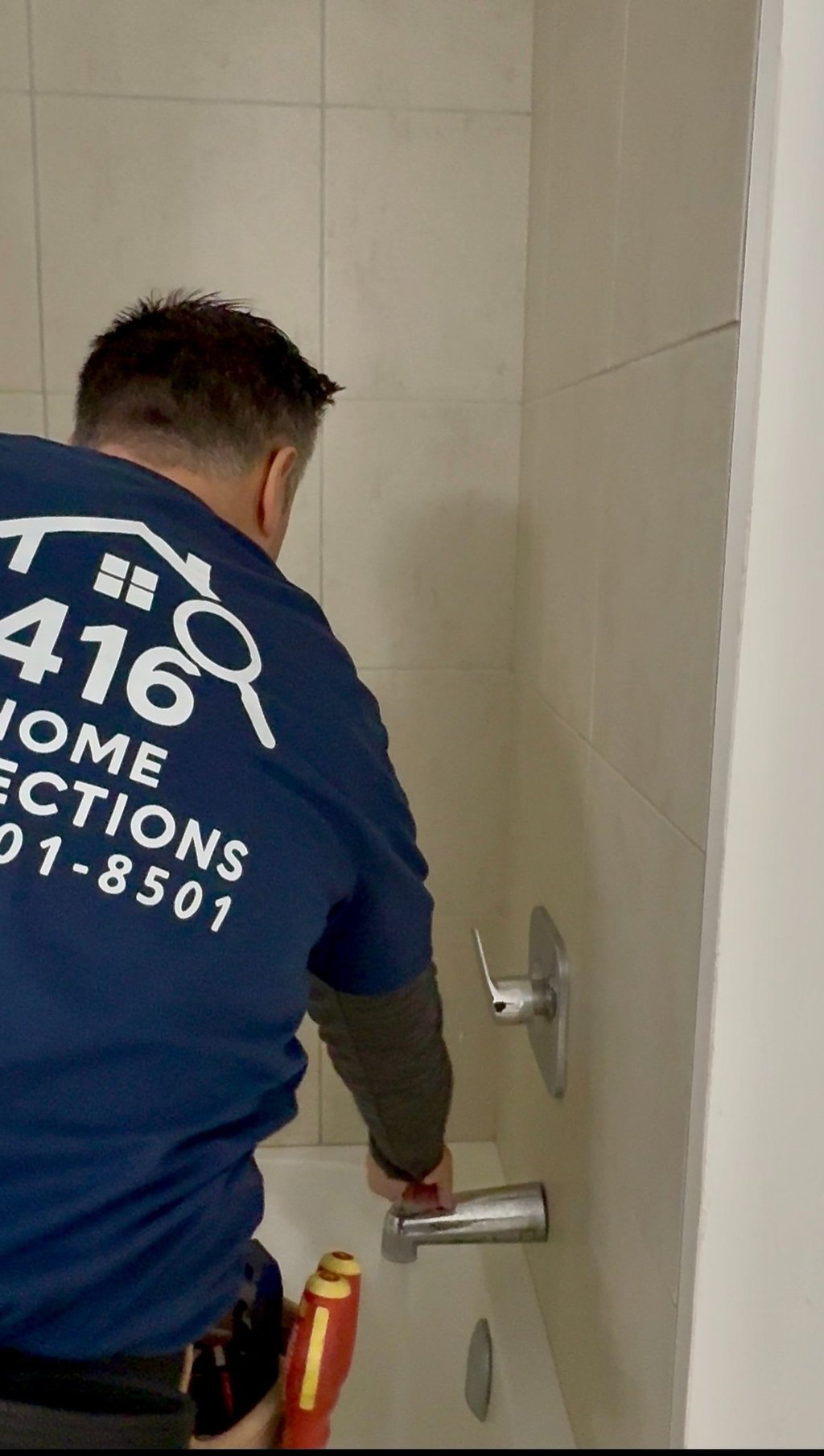 Professional home inspector checking a bathtub faucet and shower fixtures for water pressure and leaks.