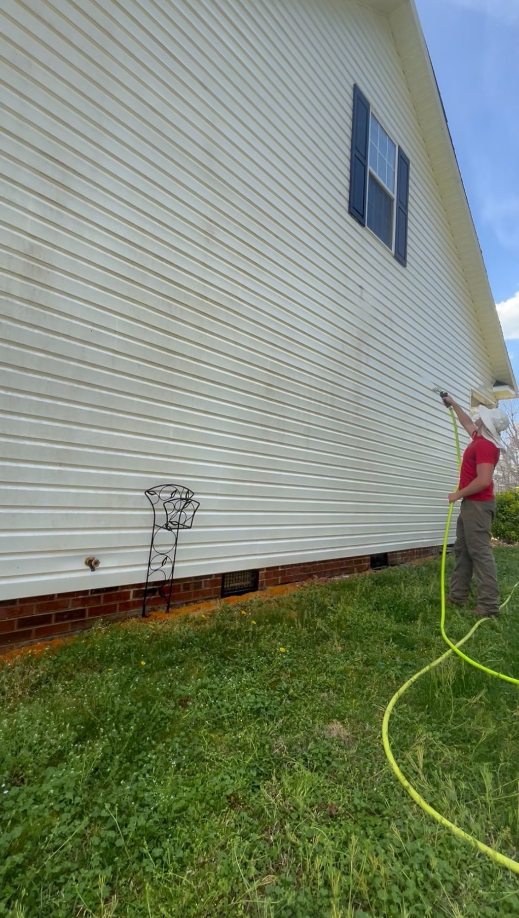 Man in gear soft washing white vinyl siding: gentle mist clears mildew, Lenoir pressure washing pro