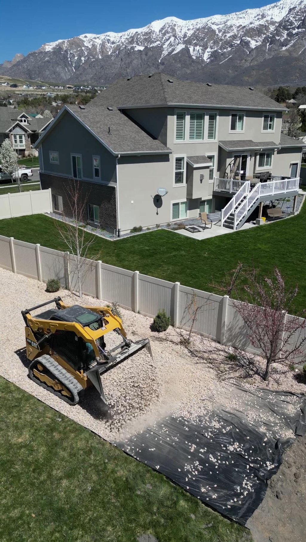 skid steer dumping landscape rock at residential home 