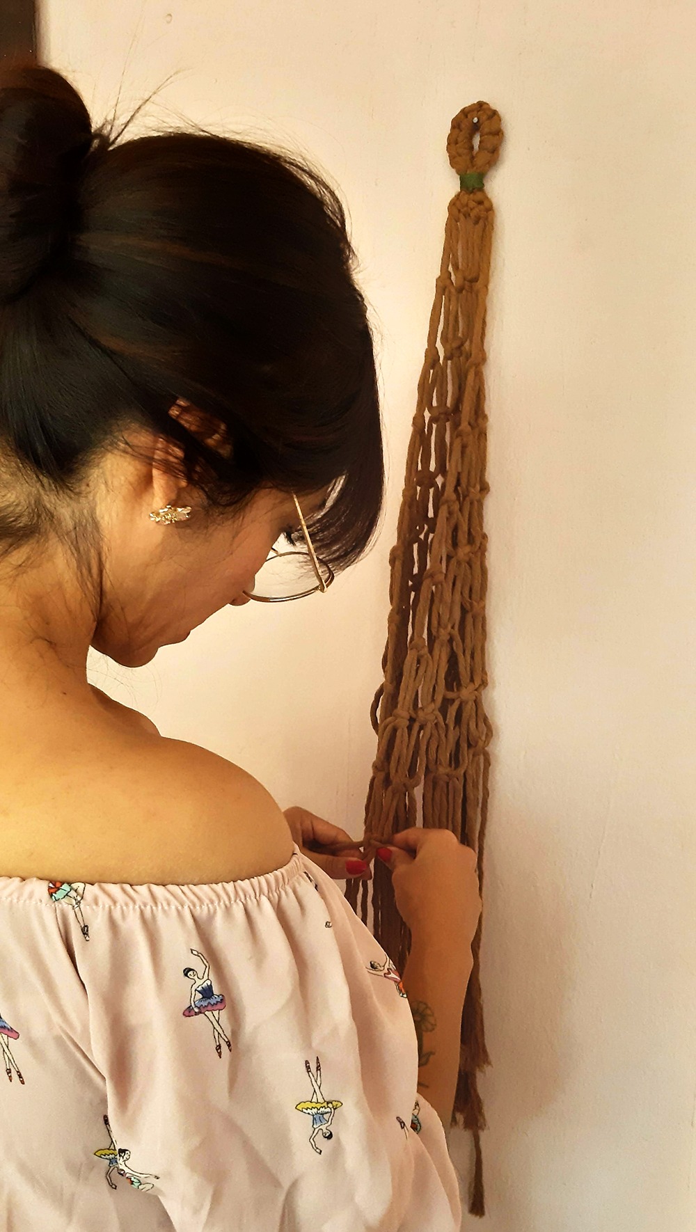 mujer haciendo un frutero de macrame en un taller, haciendo nudo por nudo.