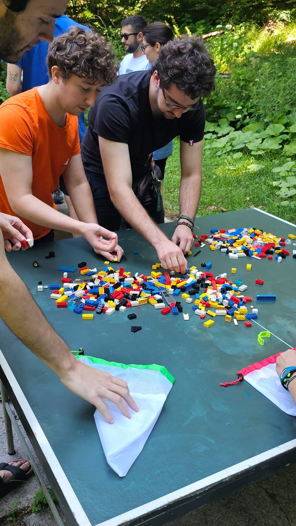 a group of people standing around a table with legos