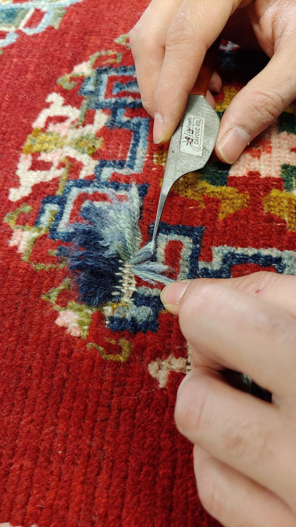restauratore riannodando un tappeto nella ricostruzione di un buco