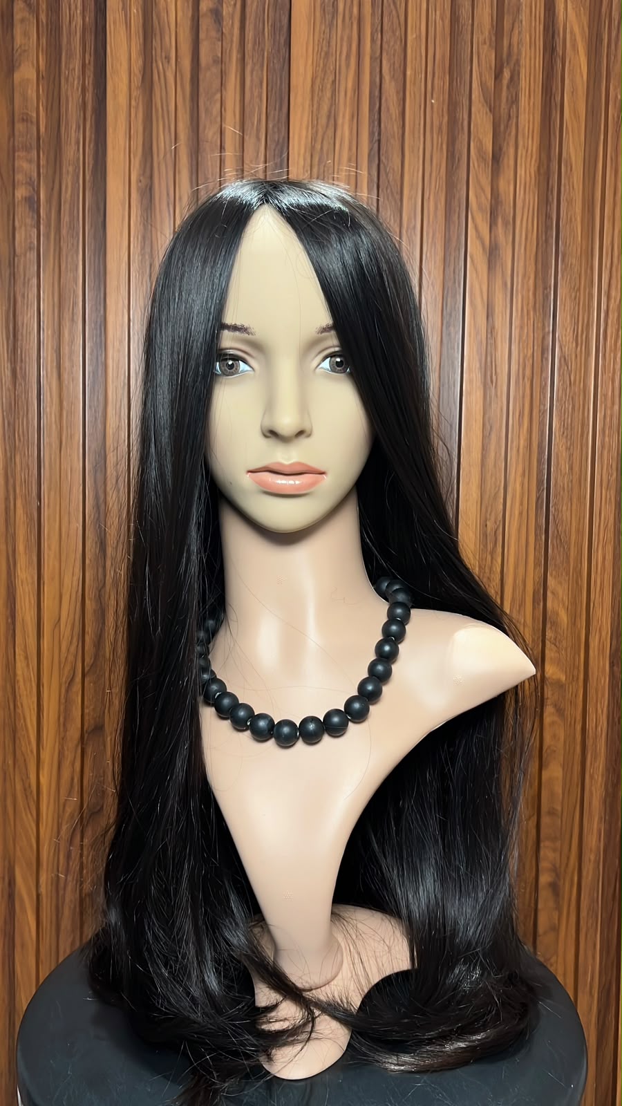 Long straight black hair wig displayed on a mannequin head with a wooden background.