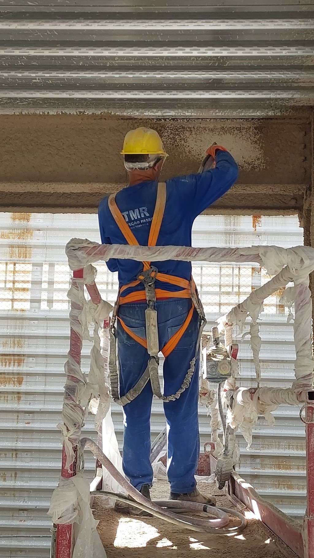 Homem Aplicando Argamassa Contra Fogo em Estrutura Metálica