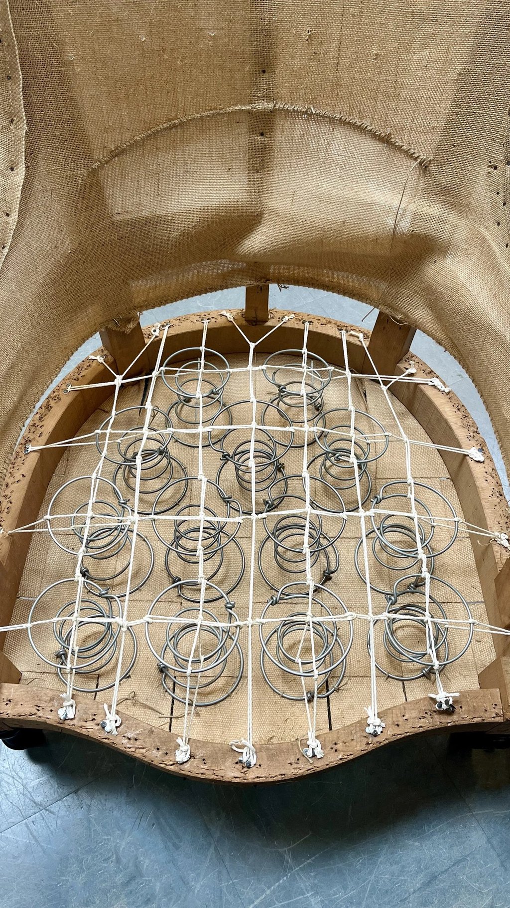 Carcasse d'un fauteuil crapaud avec sur le sanglage des ressorts guindés par des cordes