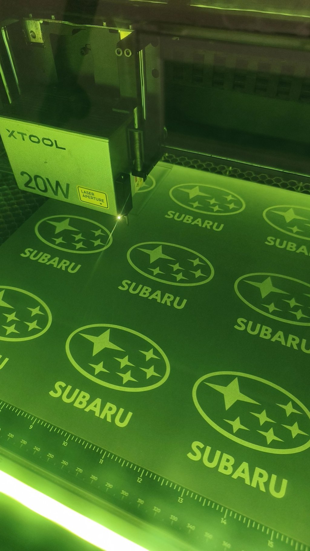 Graveuse laser XTOOL en action, gravure de logos Subaru sur médium mélaminé graphite