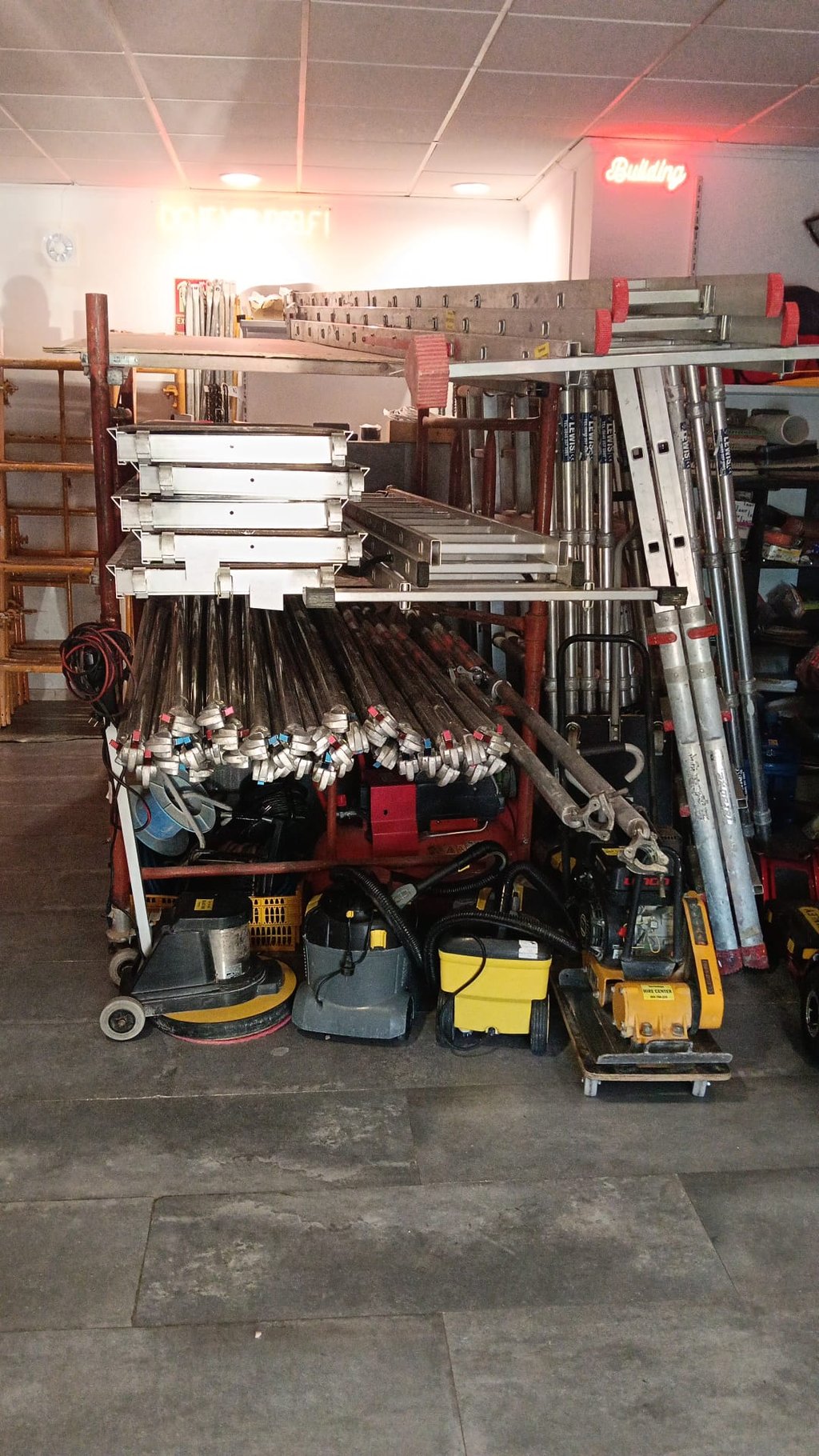 Professional scaffolding equipment, aluminum ladders, and industrial cleaning tools stored in a warehouse.