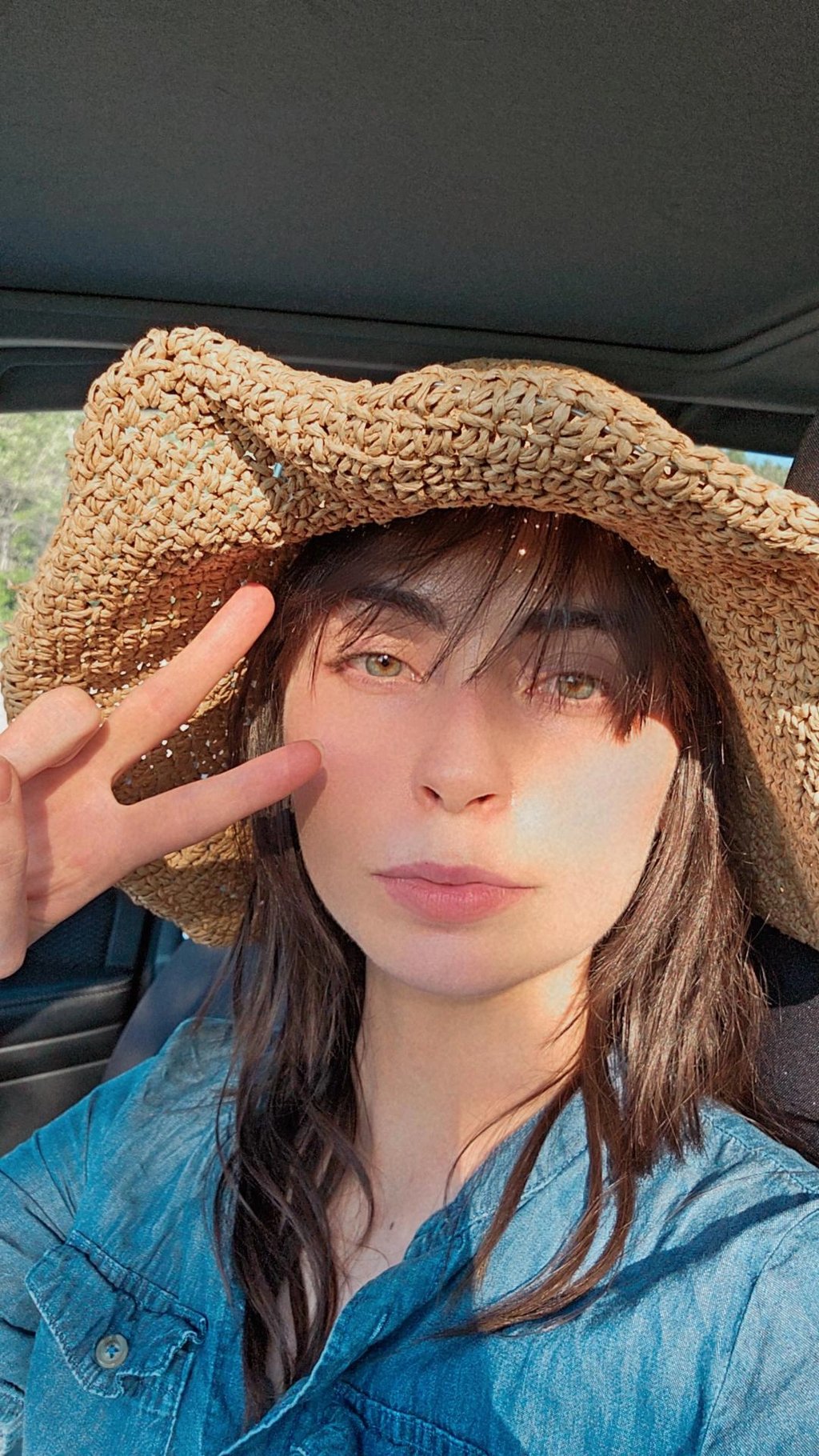 a woman in a straw hat with a straw hat on doing peace sign